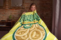 a woman holding up a large bag of onion rings on top of a bed in front of a brick wall