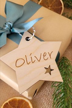 a wooden ornament with the word oliver on it next to sliced oranges