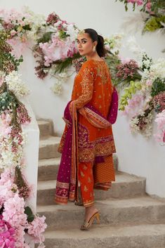 Pakistani Wedding Dress in Salwar Kameez Dupatta Style is a traditional attire that will give you a breathtaking look that is a perfect blend of trend and royalty. Sequins, dabka, naqshi, and zardosi make this Salwar Kameez an epitome of beauty and your priority to have a stunning look. Pakistani Kameez: The Kameez in an alluring orange shade and it comes in net fabric. The beautiful hand-crafted details of goldwork and embroidery enhance the glamour of this kameez. Crystals, zardosi, dabka, naqshi, and sequins give a glamorous touch to the beautiful kameez. Salwar Kameez: The heavily embellished kameez is paired with salwar, creating a lavish Pakistani Wedding Dress. The salwar is in orange color and is adorned with block print and embellished borders. Embroidery and gold work make this P Bollywood Style Sharara With Naqshi Detail, Bollywood Style Sharara With Naqshi, Designer Nida Sharara With Pallu, Traditional Naqshi Dola Silk Sharara, Eid Naqshi Sharara In Dola Silk, Eid Naqshi Dola Silk Sharara, Designer Dabka Sharara In Shantoon, Designer Naqshi Lawn Suit In Chinon, Designer Dabka Jamawar Lehenga