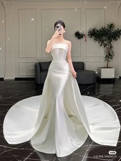 a woman in a white dress standing on top of a black and white marble floor