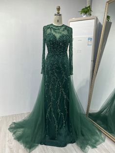 a green evening gown with sequins on the shoulders and long sleeves is displayed in front of a mirror