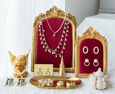 an assortment of jewelry is displayed on a white tablecloth with gold trimmings