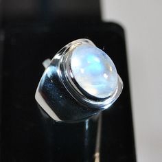 This sterling silver ring with blue moonstone setting has a stone of very good quality, because it has transparency with a beautiful blue reflection. The effect is enhanced because underneath the stone the setting is open which enables the light to pass through. The stone setting work is done with a hand tool which ensures a clean and neat finishing.  DO NOT FORGET TO GIVE YOUR FINGER SIZE WHEN SENDING THE ORDER. U.K. finger sizes available:  N, O, Q, S, T. U.S. finger sizes available:  7, 7 ½, Formal Moonstone Ring With Polished Finish, White Gold Cabochon Moonstone Ring, Modern Silver Moonstone Ring With Polished Finish, White Polished Moonstone Ring, White Gold Moonstone Cabochon Ring, Modern Sterling Silver Moonstone Ring, Modern Silver Round Moonstone Ring, Modern Sterling Silver Round Moonstone Ring, Silver Moonstone Ring With Oval Cabochon