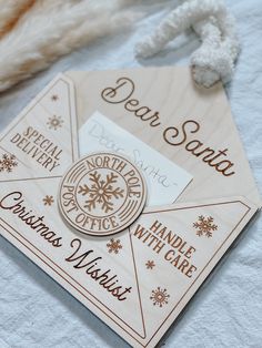 a wooden christmas card with the words dear santa written on it and snowflakes