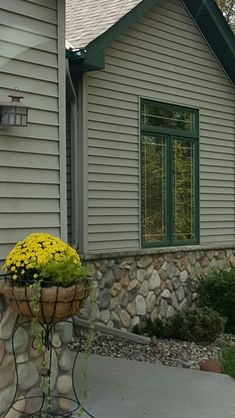 there is a planter with yellow flowers in front of the house