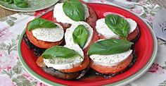 a red plate topped with tomatoes and mozzarella on top of a floral table cloth