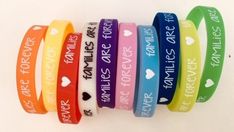 five different colored rubber bracelets with words on them and hearts in the middle one