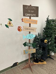 a wooden sign sitting next to a small christmas tree in an office building with signs on it