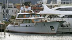 two boats docked in the water next to each other near some buildings and yachts