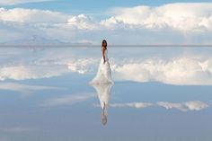 a woman in a white dress is walking across the water