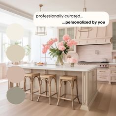 a white kitchen with pink flowers on the island and two stools in front of it