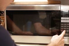 a man pointing at a microwave on top of a counter