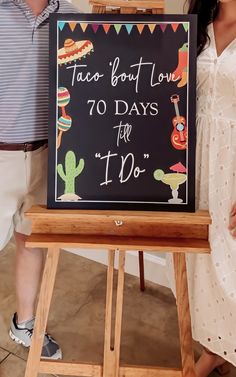 two people standing behind a sign that says taco bout love 70 days left to do