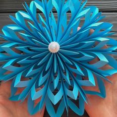 a person holding a blue paper flower in their hand