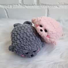 two crocheted stuffed animals sitting next to each other on a white fur covered surface