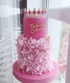 a birthday cake with pink ruffles and a crown on top