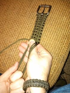 a person is holding on to a green rope with a metal buckle in their hand