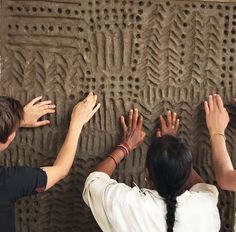 three people reaching up to touch the wall with their hands and fingers on top of each other