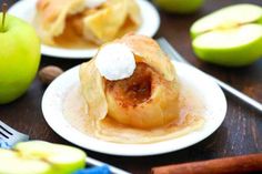 apples and cinnamon rolls on white plates with silverware next to them, all topped with whipped cream