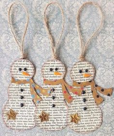 three snowmen made out of old book pages are hanging from twine with string