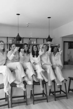 a group of women sitting on top of wooden stools