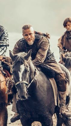 a man riding on the back of a brown horse next to other men in armor