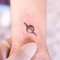 a small saturn tattoo on the left side of the ankle is shown in black ink