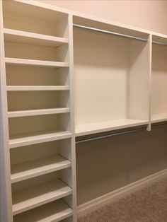 an empty closet with white shelves and carpet