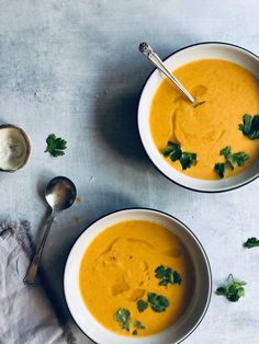 two bowls filled with soup and garnished with parsley