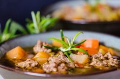 a close up of a bowl of soup with meat and vegetables