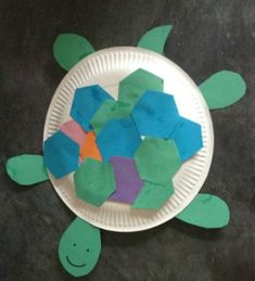 a paper plate with cut out pieces of sea turtle shapes on it, sitting on a black surface