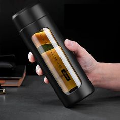 a hand holding a black and gold flask bottle