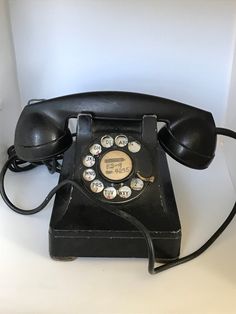 an old black phone sitting on top of a table