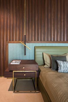 a bedroom with a bed, nightstand and wooden paneling on the wall behind it