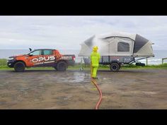 an orange truck is parked next to a camper and a man in yellow jacket