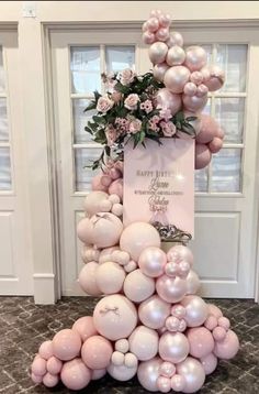 a pink and white balloon tower with flowers on top, balloons in the shape of a pyramid