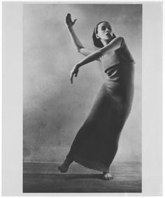 a black and white photo of a woman in a long dress with her arms outstretched