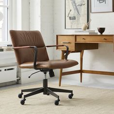 a brown leather office chair sitting in front of a desk with a computer on it