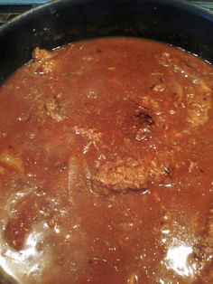 a pan filled with meat and sauce on top of a stove