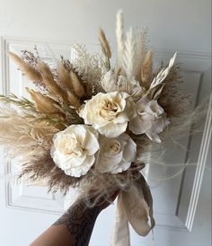 a bouquet of flowers and feathers in someone's hand on the door way to their home