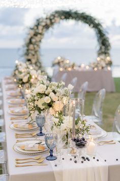 a long table with white flowers and candles is set up for an outdoor wedding reception