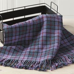 a plaid blanket in a metal basket on the floor