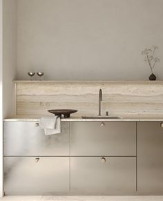 a modern kitchen with stainless steel cabinets and counter tops, along with a vase on the wall