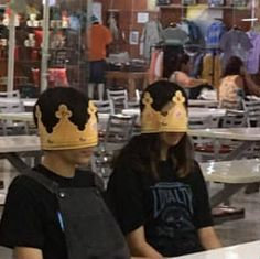 two people wearing crowns sitting at a table