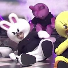 two cartoon characters are sitting on the floor with one holding a stuffed animal in front of them