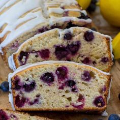 sliced loaf of lemon blueberry bread with icing and fresh berries on the side