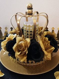 a gold and black cake with roses on it's top, sitting on a plate