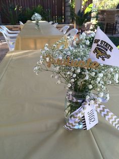 flowers are in a vase sitting on a table at a graduation party with flags and decorations