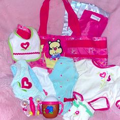 a pink bag filled with lots of baby items on top of a pink bed sheet