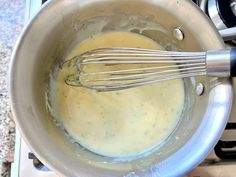 a pot filled with liquid and whisk on top of a stove burner